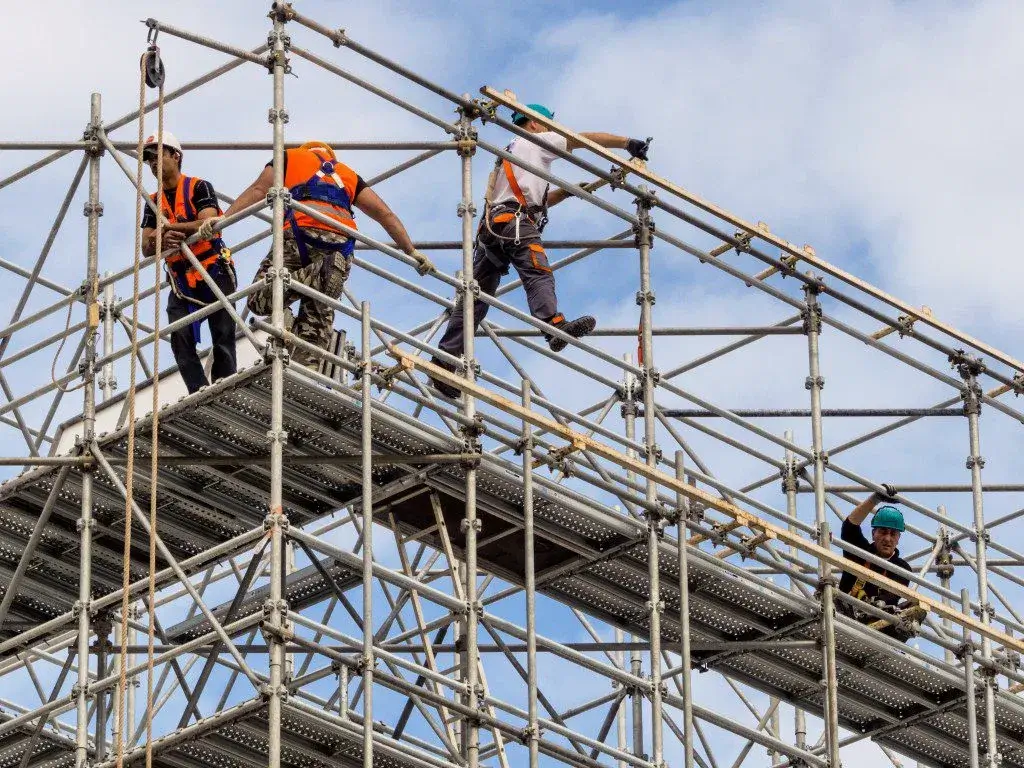 pekerja konstruksi yang sedang bekerja diatas rangkaian scaffolding